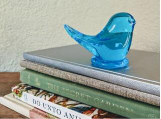 A glass Bluebird sitting on top of a stack of books